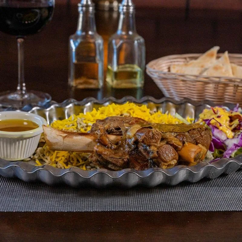 Lamb shank with saffron rice, salad, and traditional sides at Shiraz Persian Cuisine.