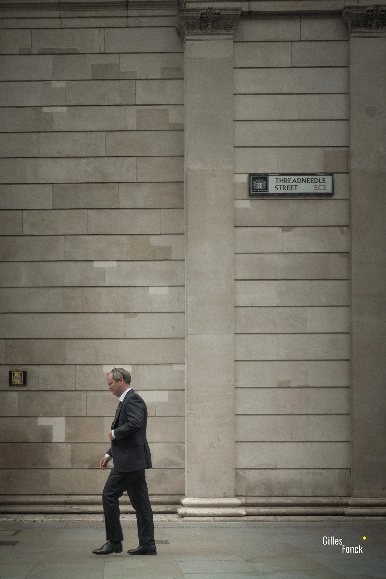 A lone man in a suit walks in front of a massive brick aface in Threadneele Street in the City of London