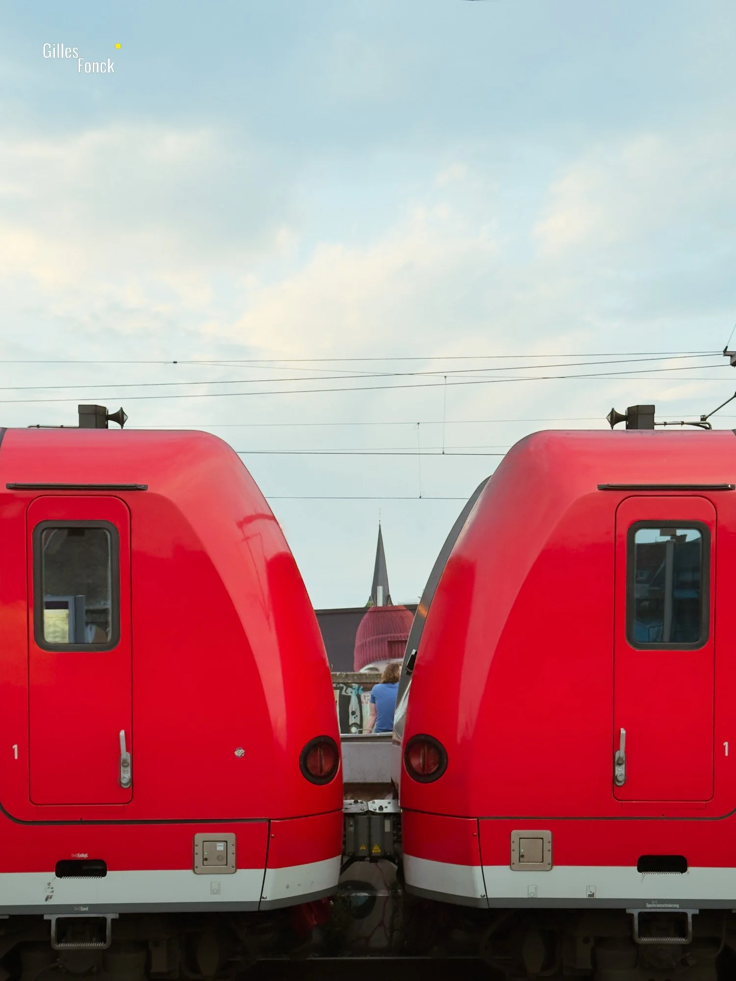 Side portrait of two bright red train coaches coupled together.
