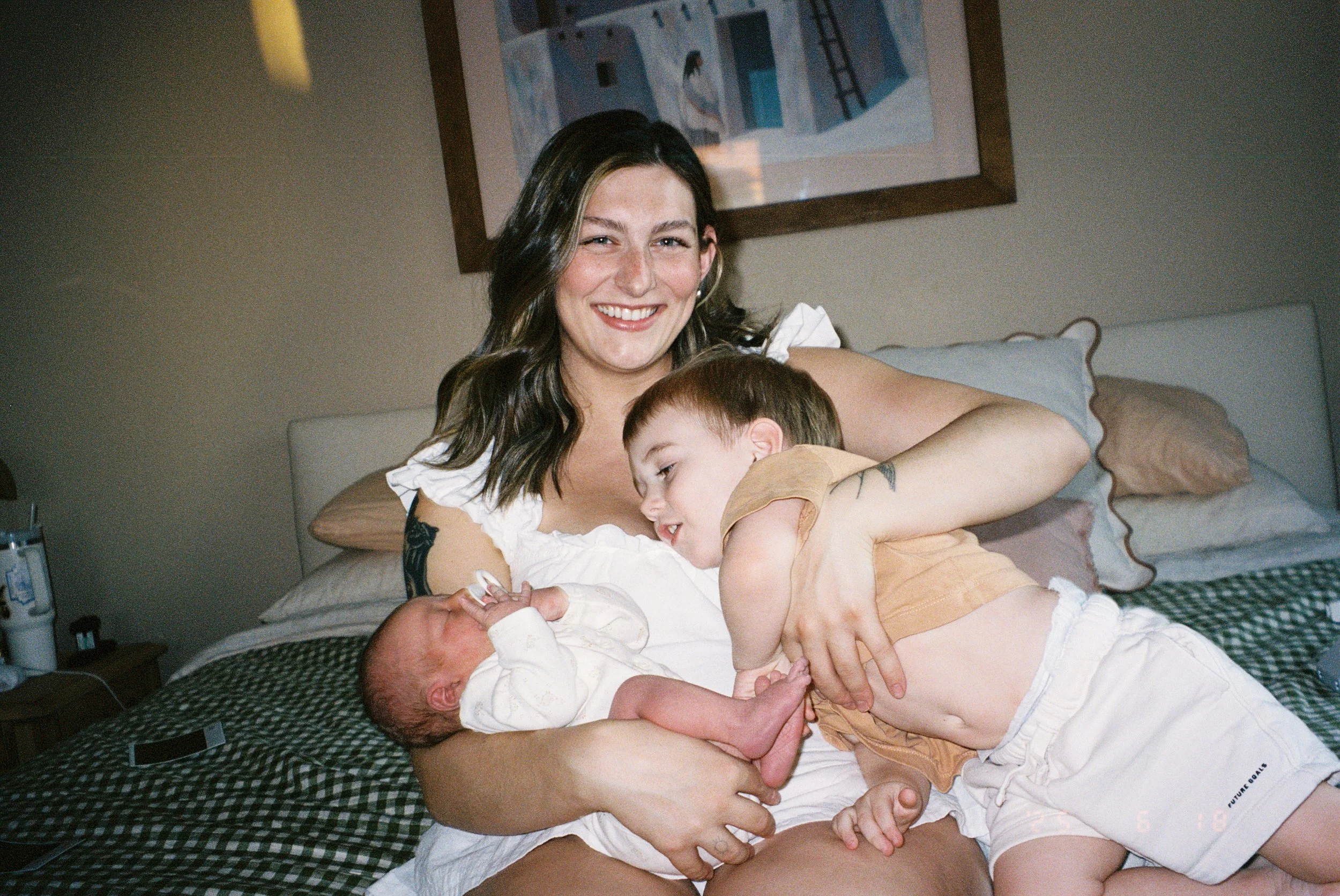 A woman with dark hair smiling as she holds two young children.