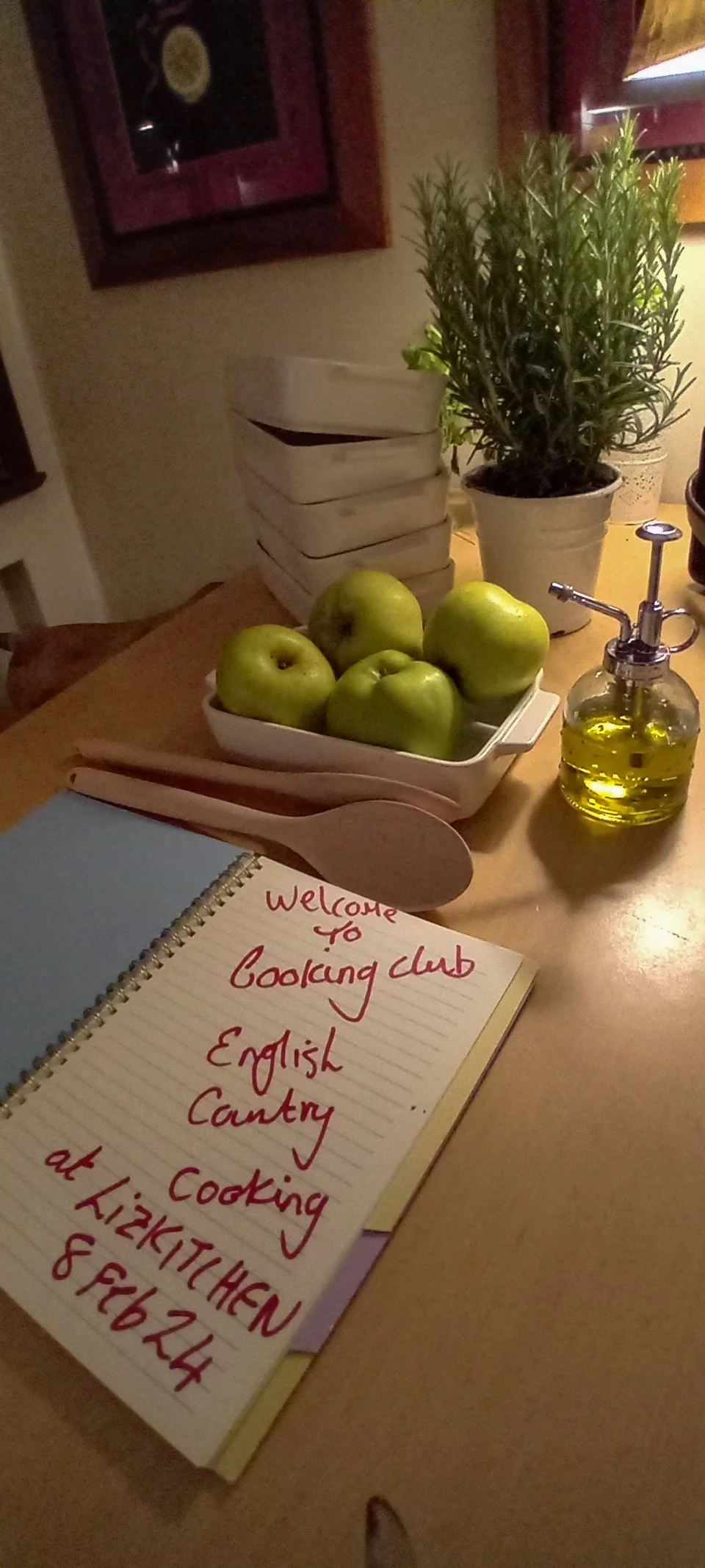Welcome notebook for English country cooking club surrounded by apples and utensils.