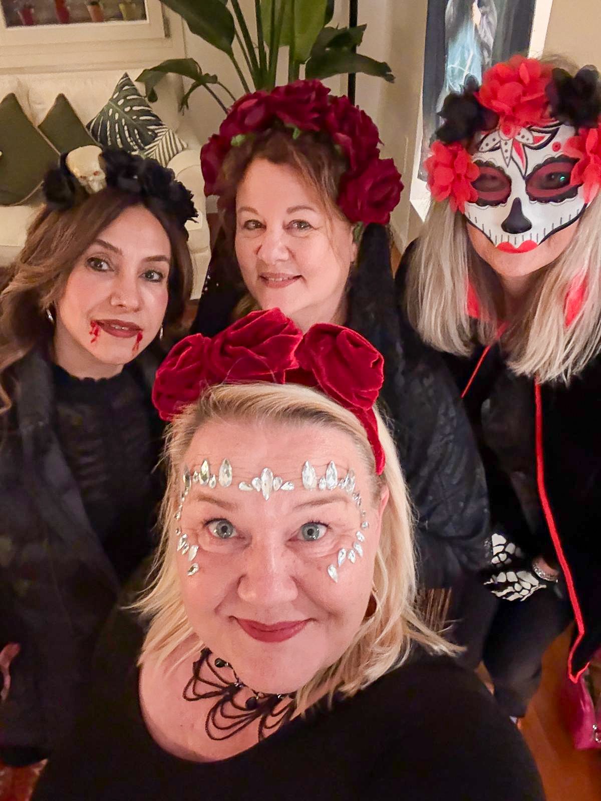 Four members wearing festive Halloween sugar skull makeup and headbands.