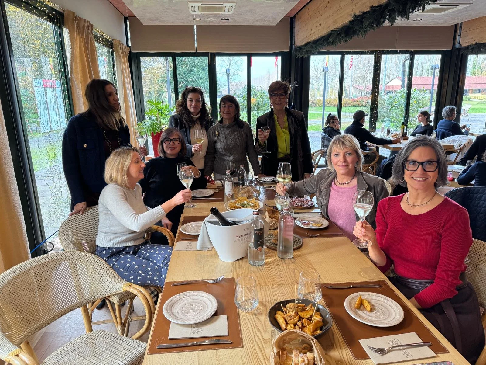 Members celebrating and raising glasses at a restaurant table during the Christmas Luncheon.