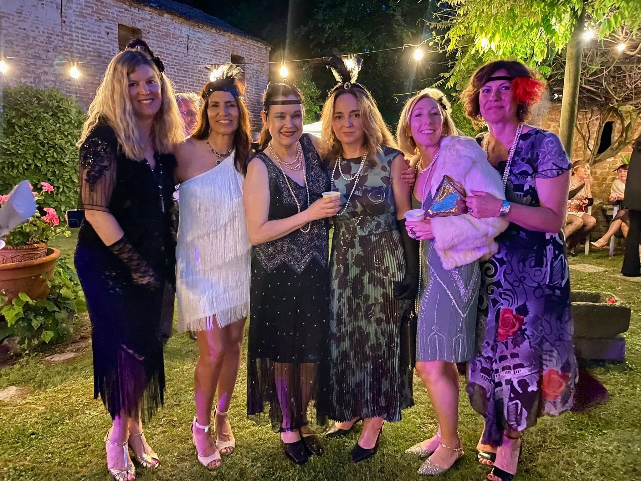 International Ladies Group members dressed in 1920s Gatsby costumes outdoors.