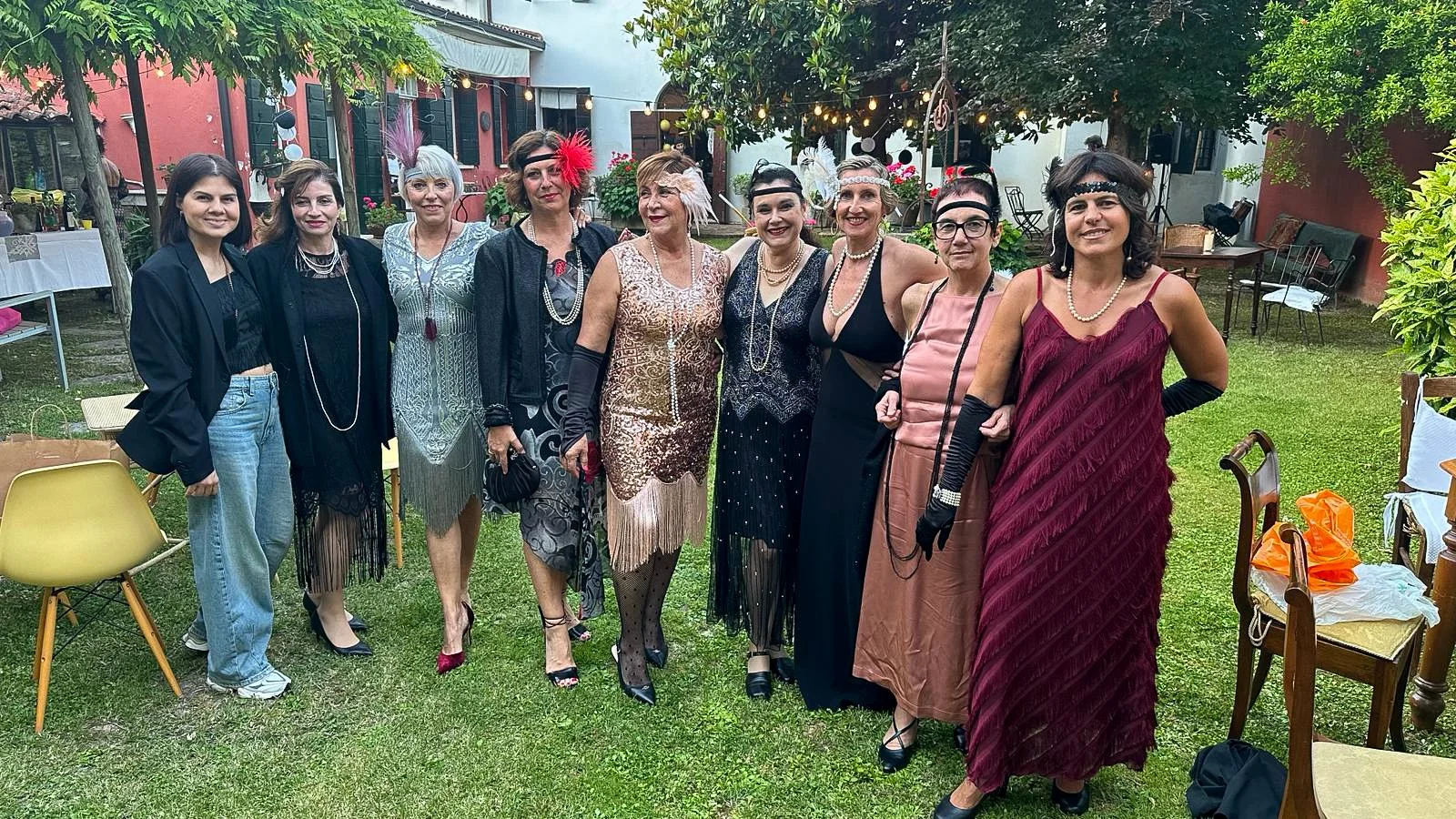 Group of members in 1920s vintage dresses posing on a lawn.