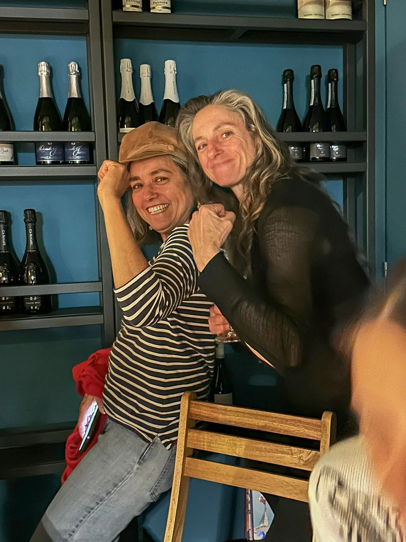 Two members posing playfully in front of a wine display.