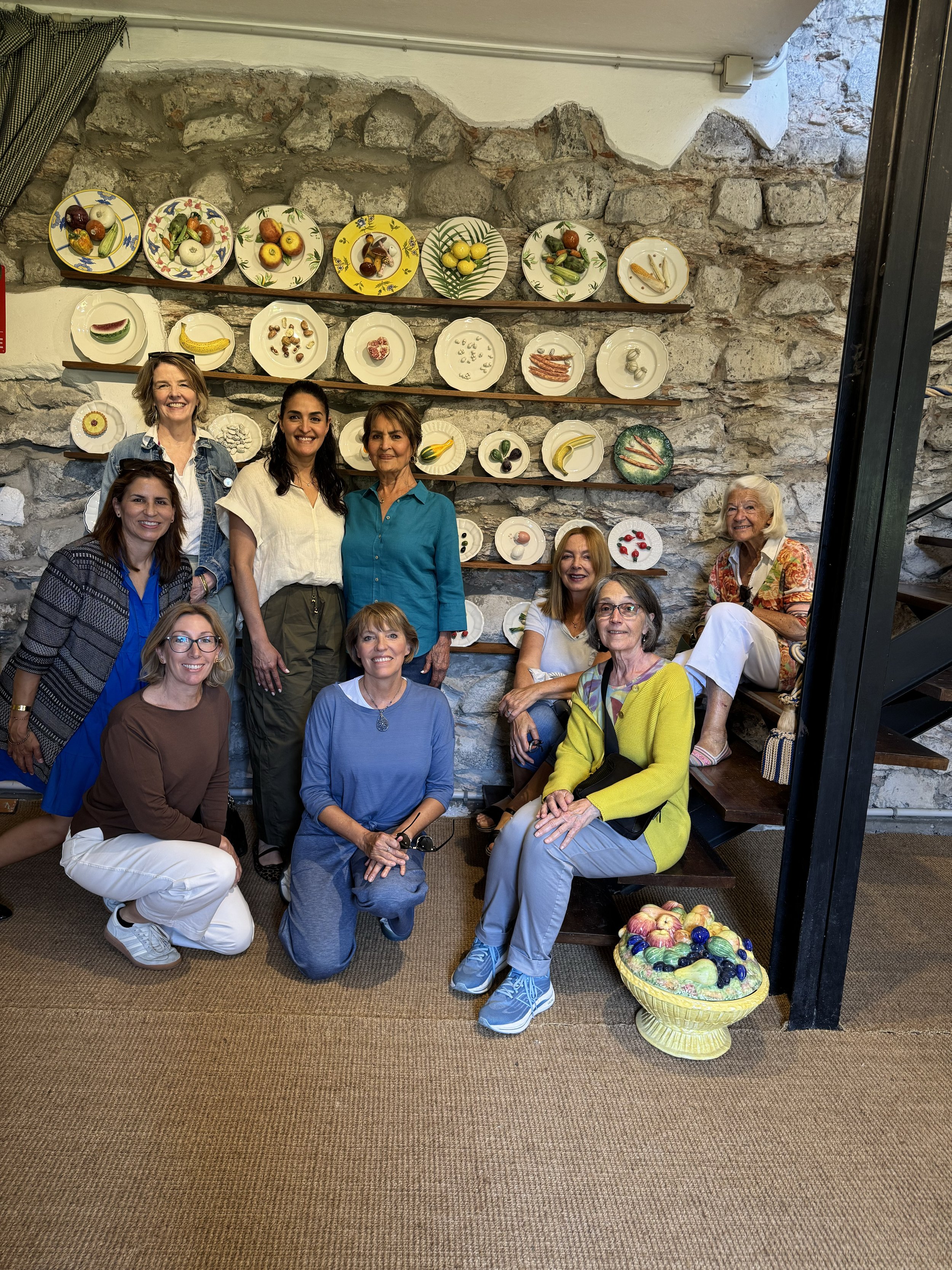 Members posing together in front of a wall of painted ceramic plates.