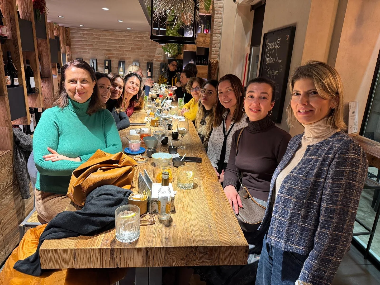Group of women sitting together at a long wooden table during an evening meetup in Padova.