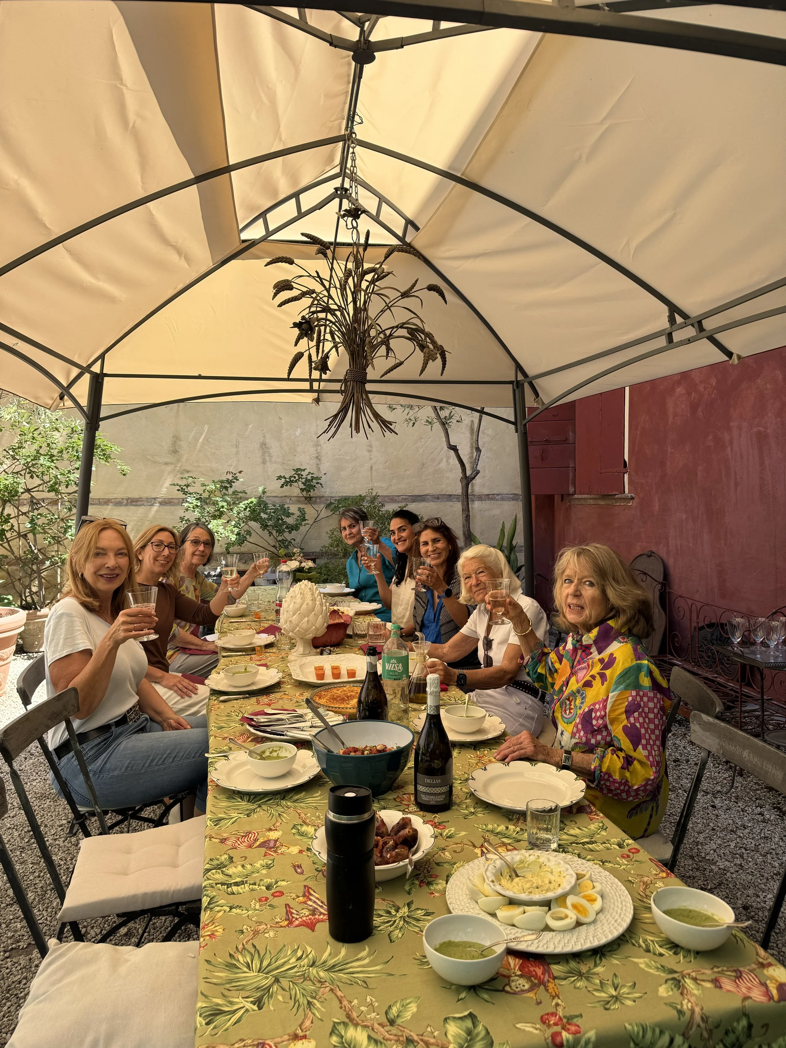 Group enjoying lunch and wine together under an outdoor garden gazebo.