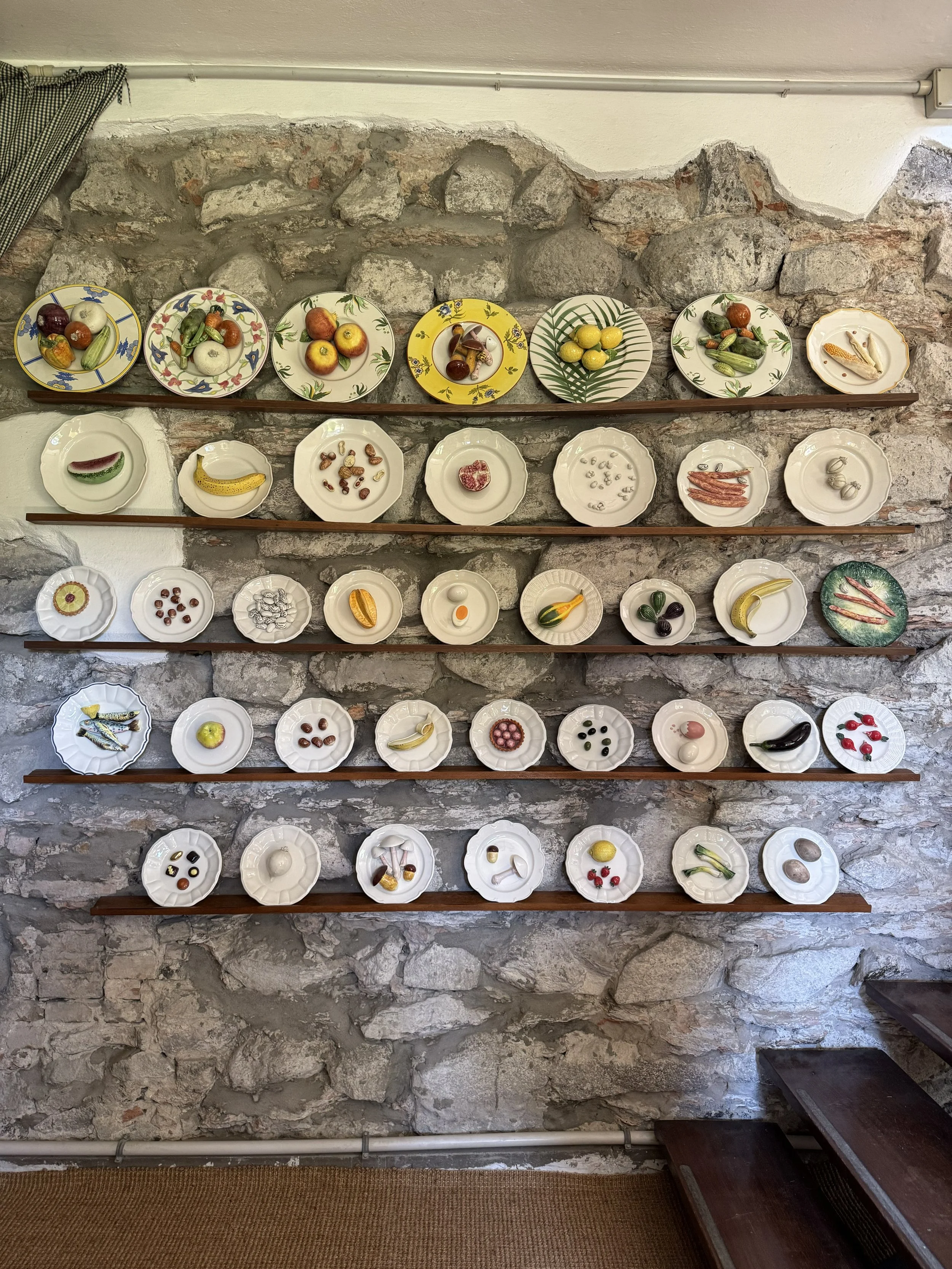 Wall display featuring hand-painted ceramic plates with fruit motifs.
