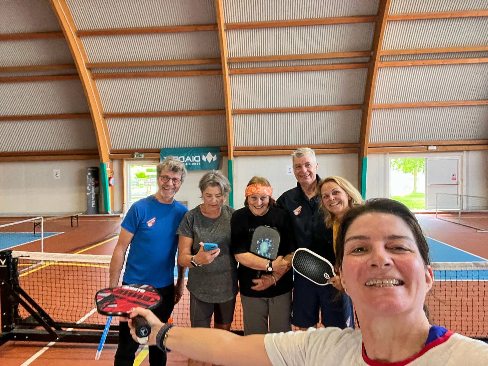 Selfie of members on a pickleball court holding paddles.