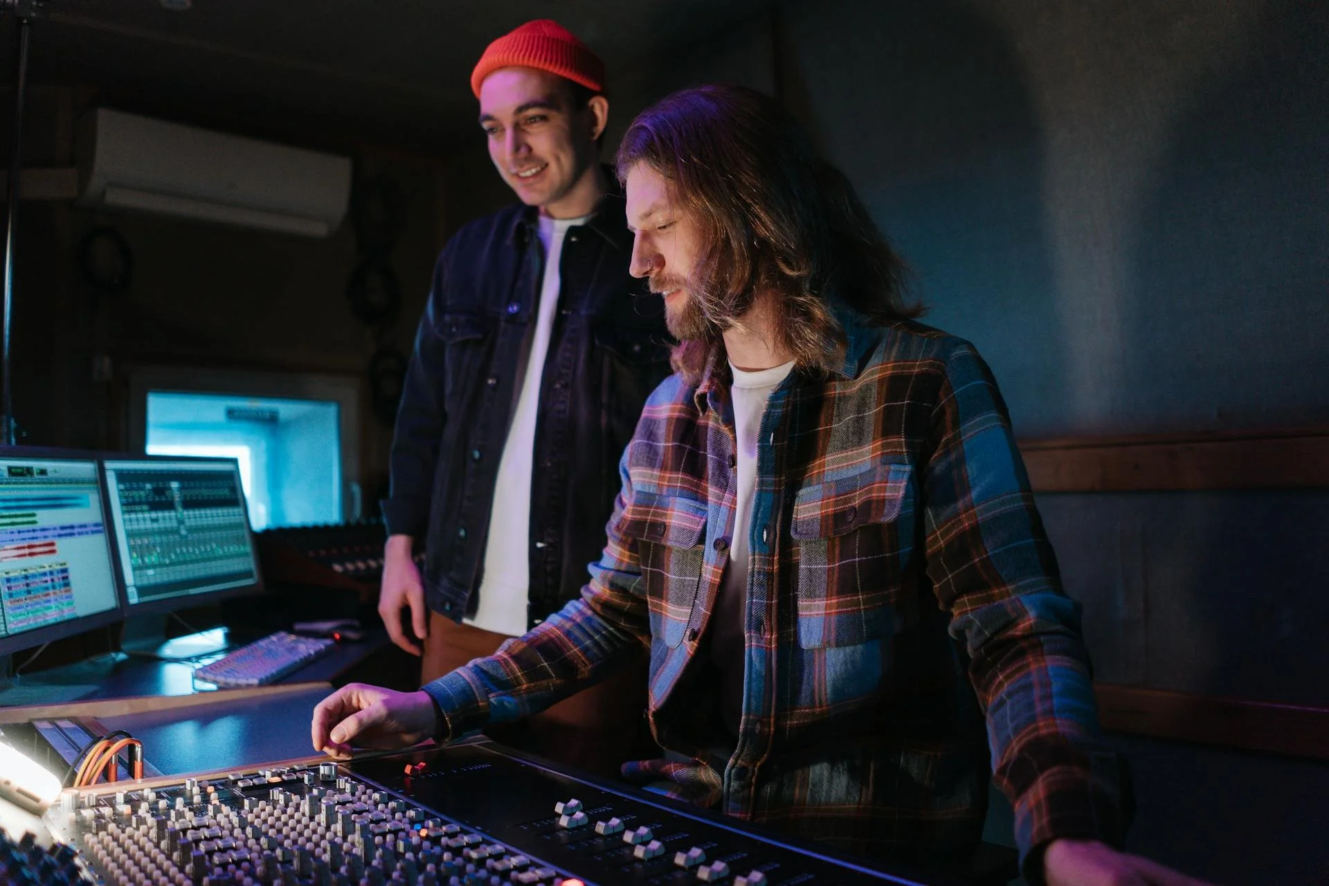 Two men in a music studio working with audio equipment and computers.