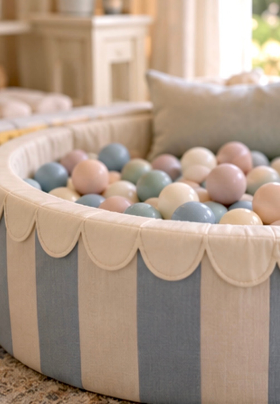 A fabric-covered ball pit with pastel-colored plastic balls in a cozy, well-lit room.