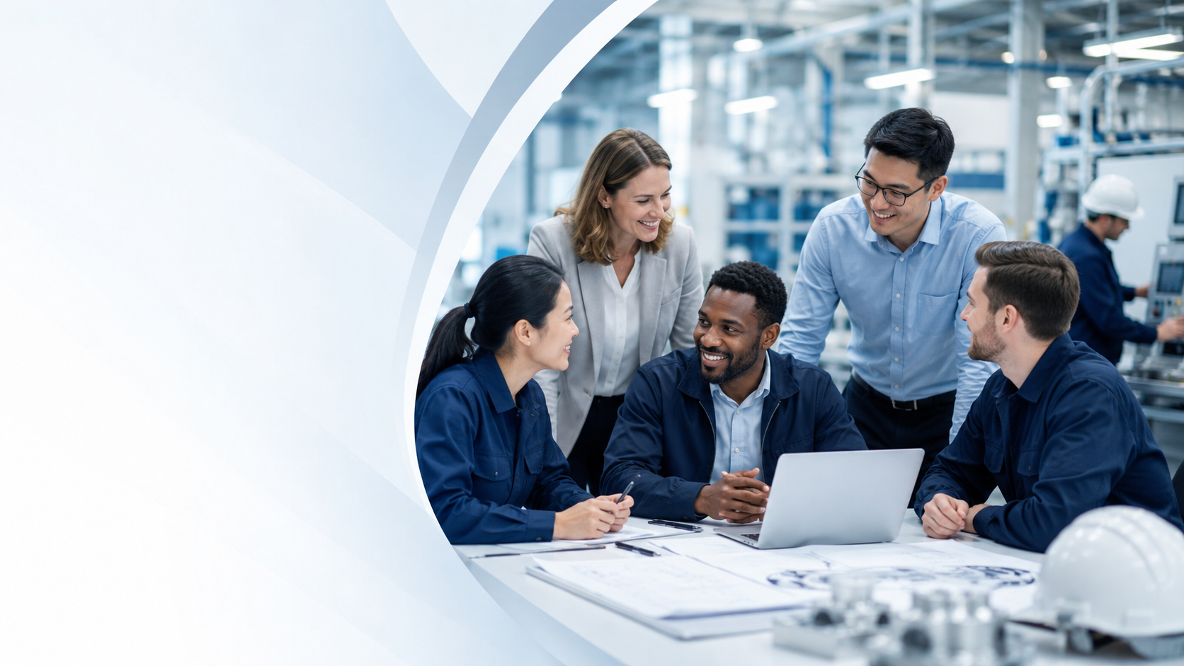 Group of five diverse professionals in an industrial setting, engaging in a discussion around a laptop at a table with blueprints and plans, with a worker in safety gear in the background.
