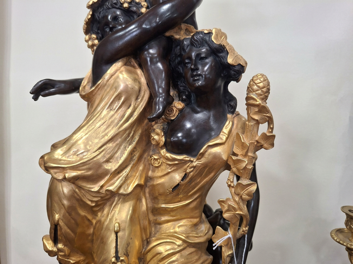 Close-up of a decorative sculpture of Black women with detailed hairstyles and flowing gold dresses, adorned with gold accessories and leaves.