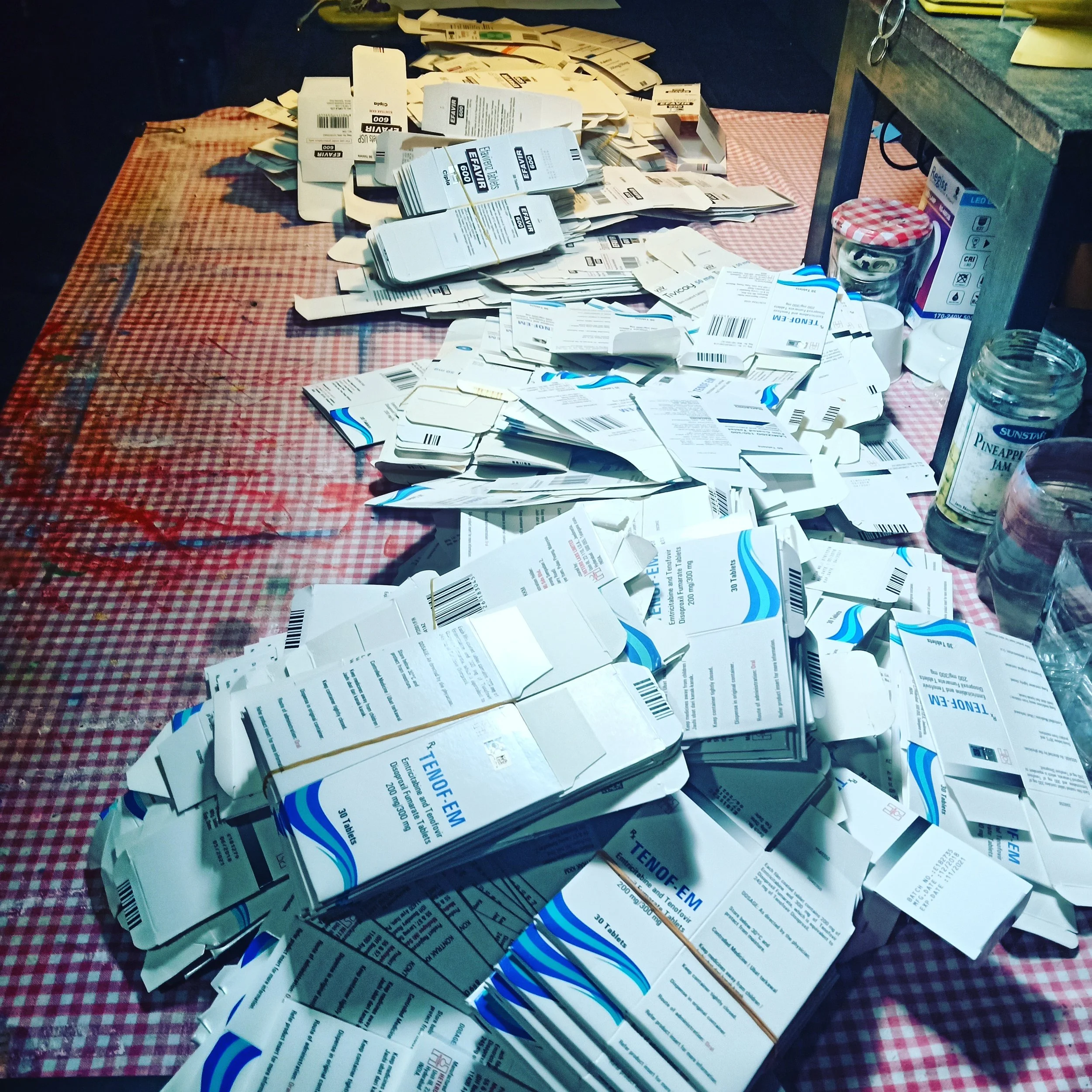 Preparing collected HIV medication packaging for gluing