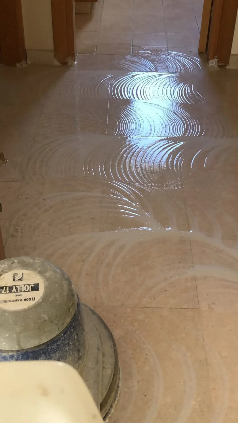 Floor being polished with a machine, leaving swirl marks and a shiny surface.