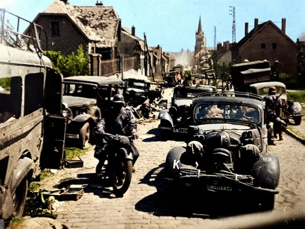 Fahrzeugkolonne mitten in einer zerstörten Stadt – kolorierte Fassung eines Fotos aus dem Original-Kriegstagebuch.
