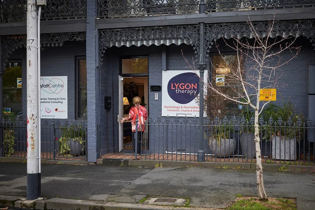 A person enters the Lygon Therapy building with signs on the building offering psychology, psychotherapy, and counselling services.