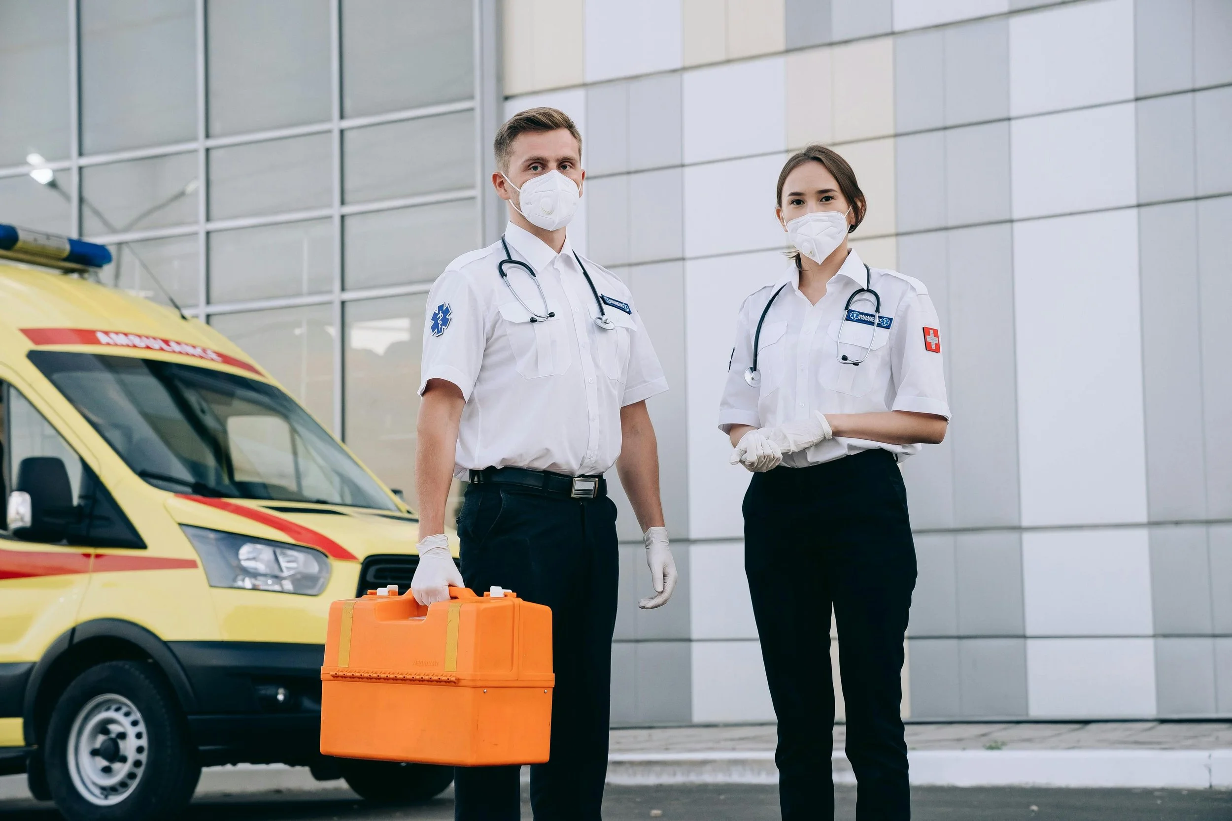 Two masked paramedics outside a healthcare setting