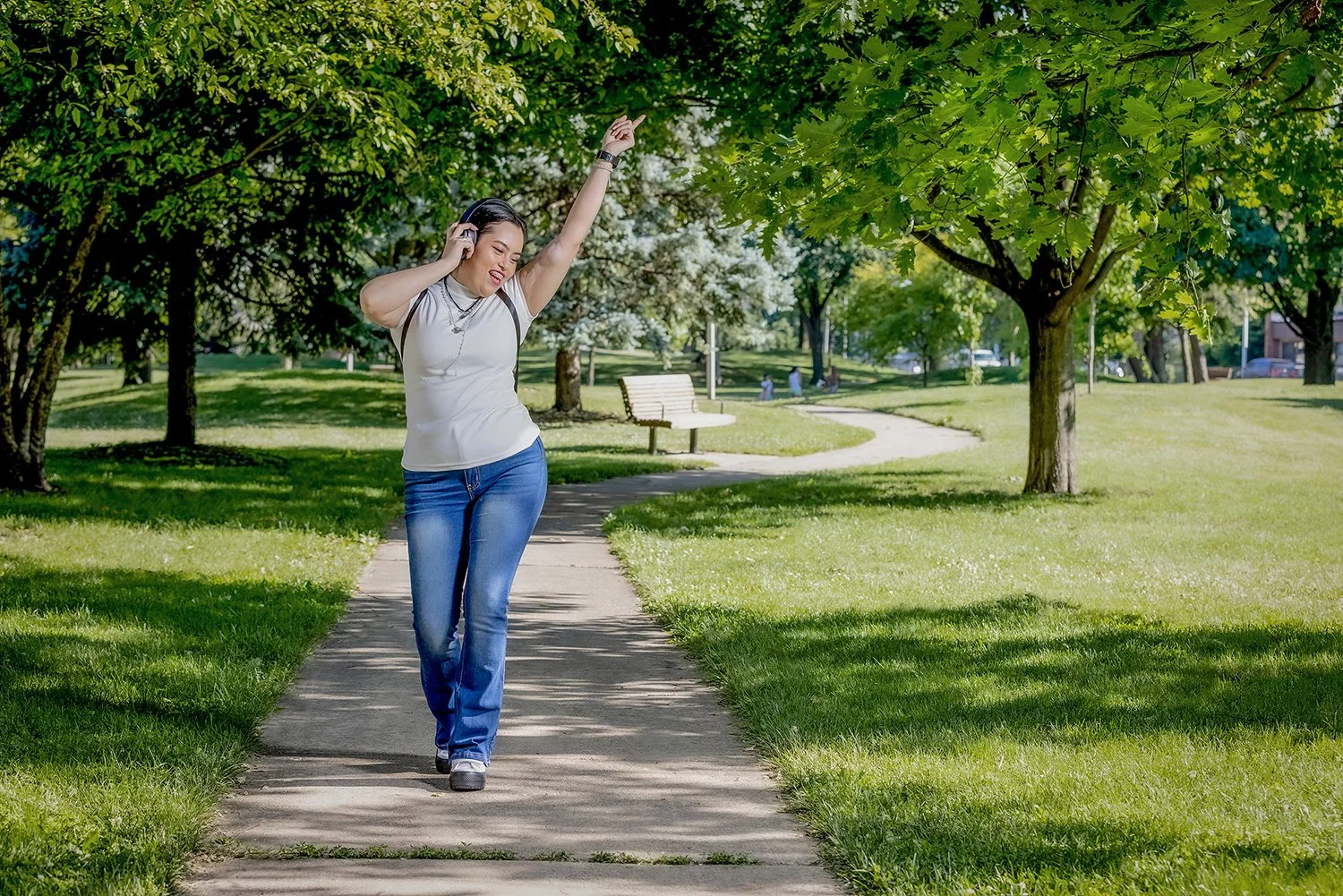 Joyful Young Woman Dancing and Listening to Music on Headphones Outside in a Park