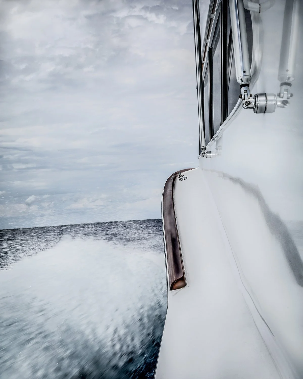 A Side Angle Perspective of a White Yacht Hull Cutting Through Ocean Water with a Large Wake