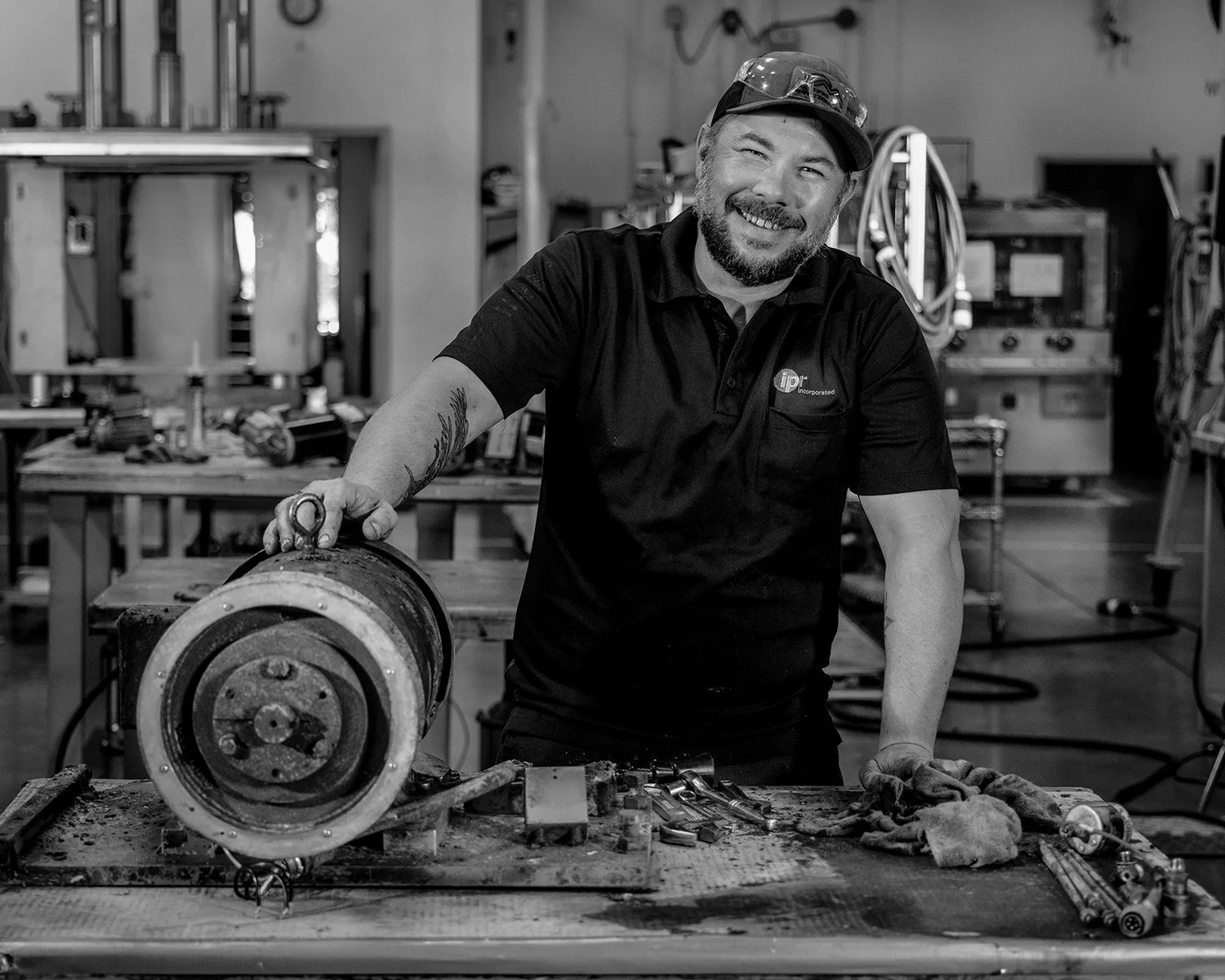 Black and White Portrait of Mechanic Next to a Hydraulic Cylinder on a Workbench