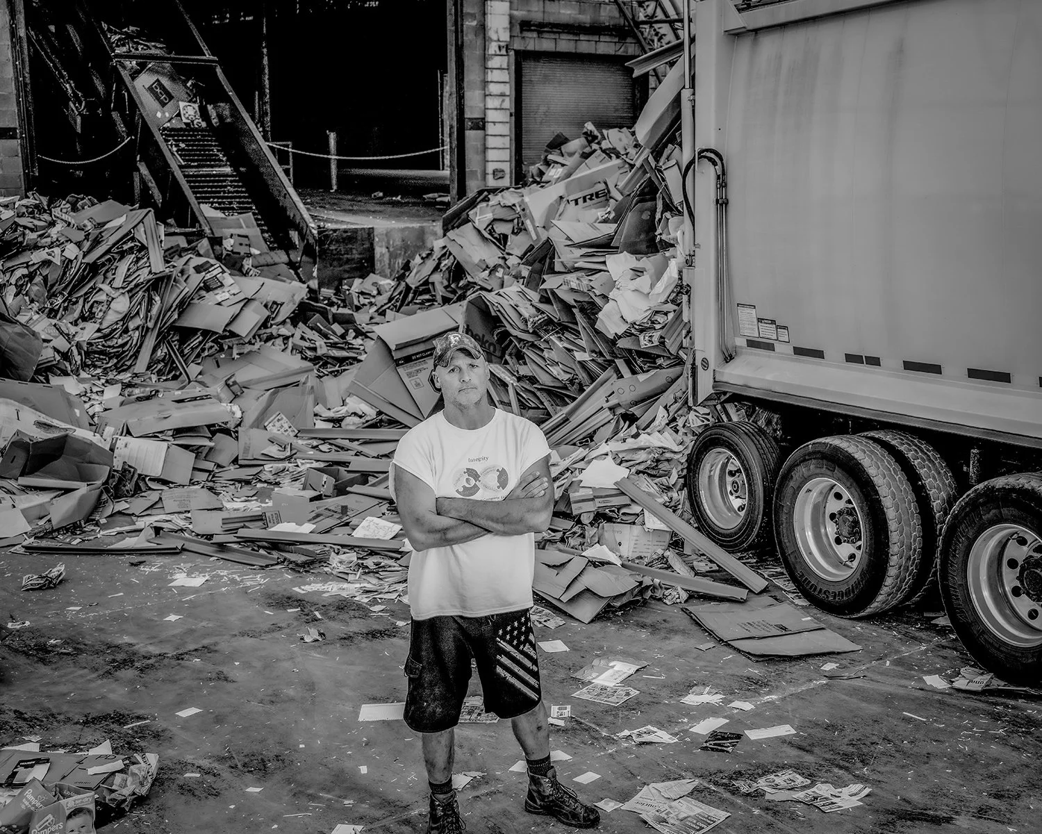 Industrial Portrait Photography of Man in Front of Mounds of Cardboard at a Recycling Plant