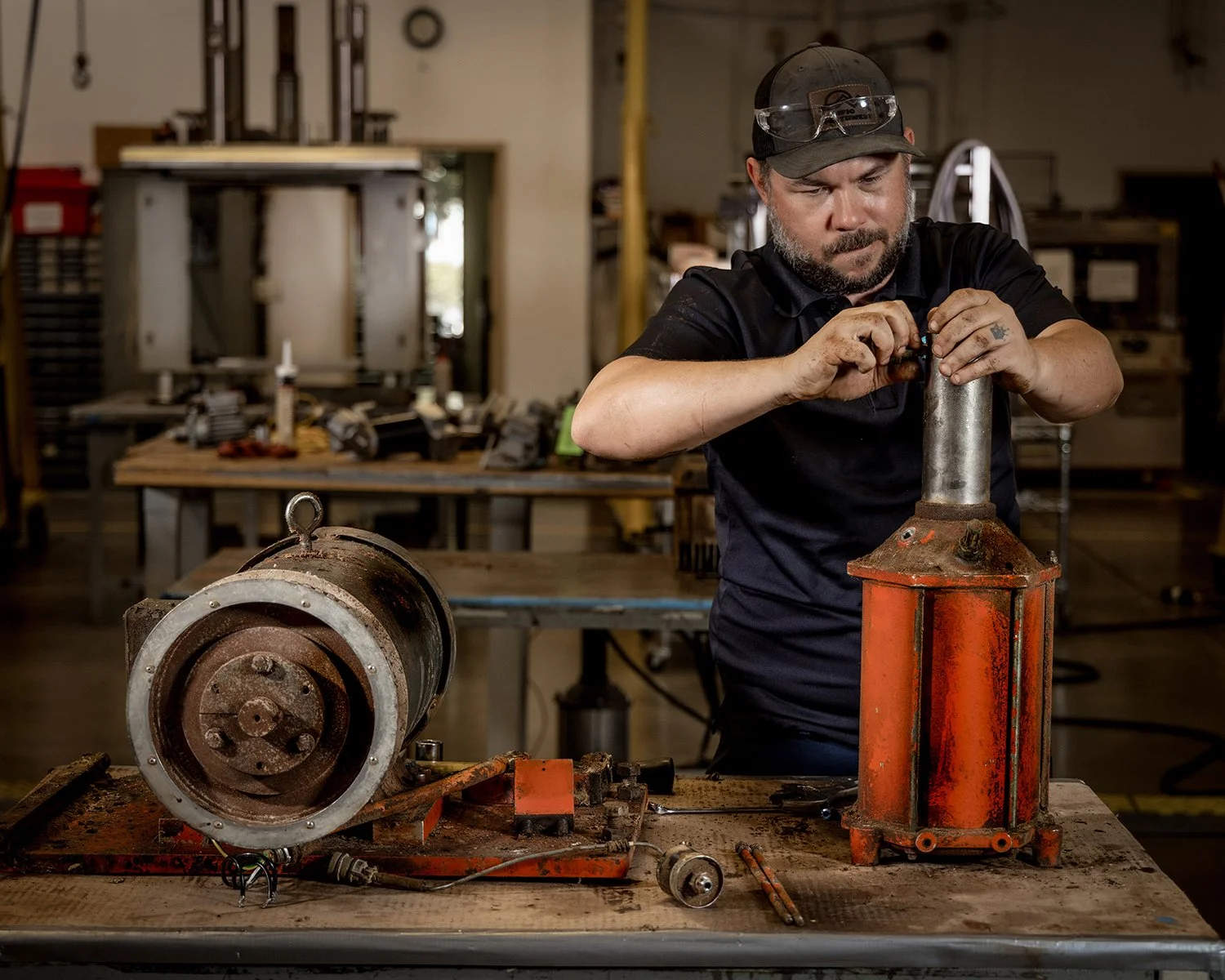 Mechanic Working on Large Industrial Hydraulic Cylinder on a Workbench