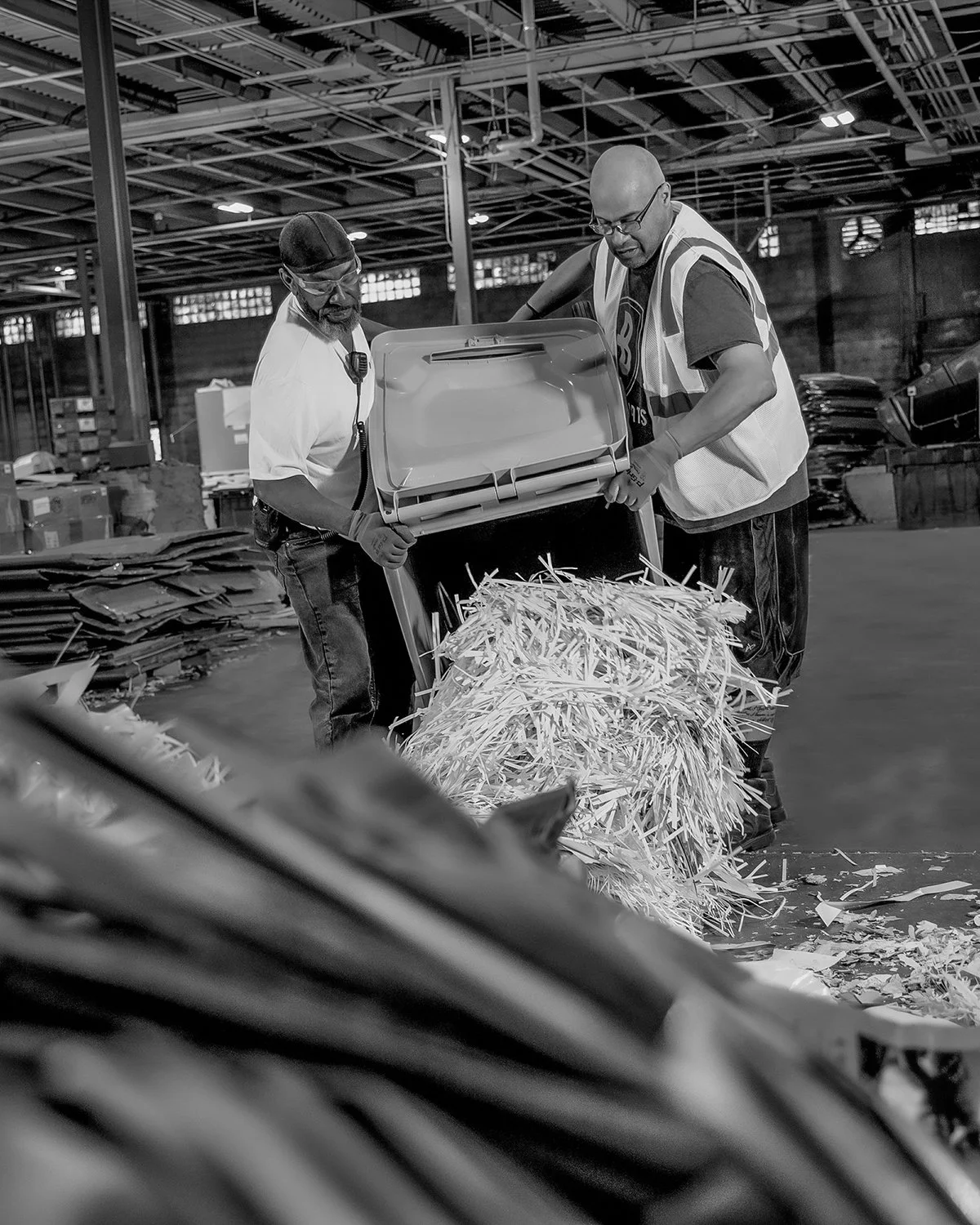 Two Men Emptying out Large Bin of Paper in a Recycling Plant