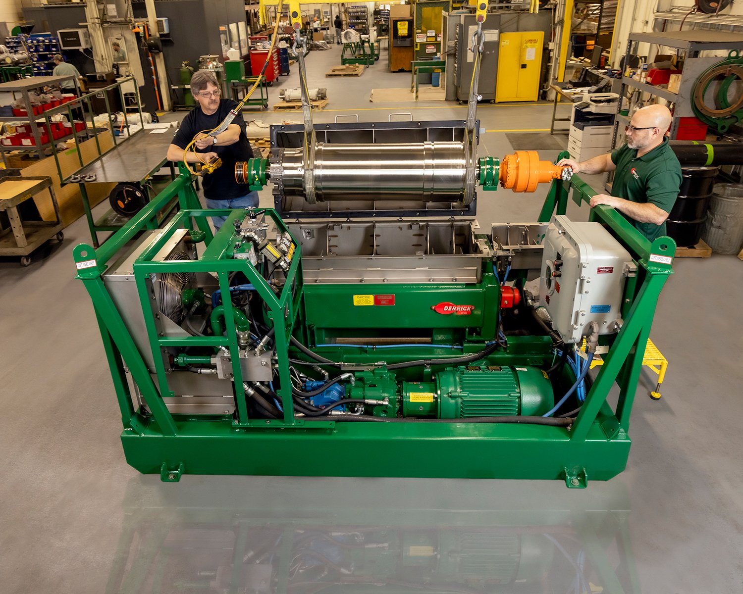 Two Technicians Assembling a Large Industrial Centrifuge Machine inside a Factory Warehouse