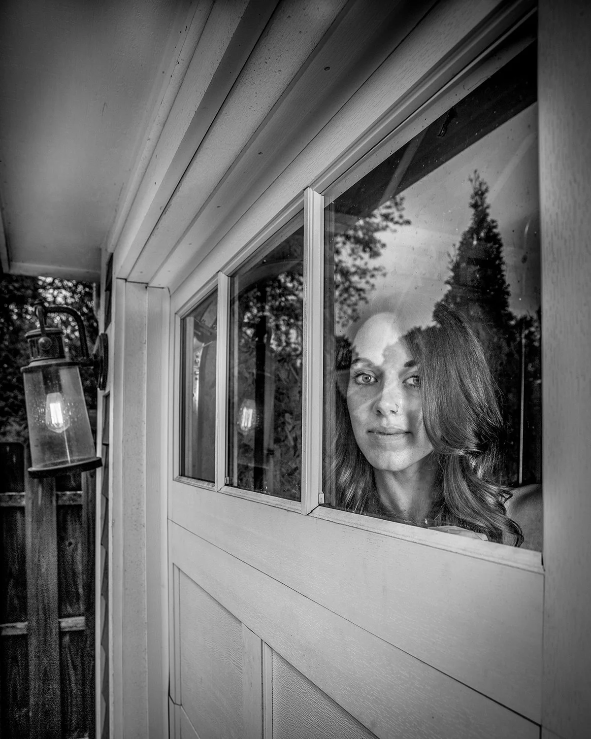 Black and White Image of Woman Looking through the Window of a Garage Door
