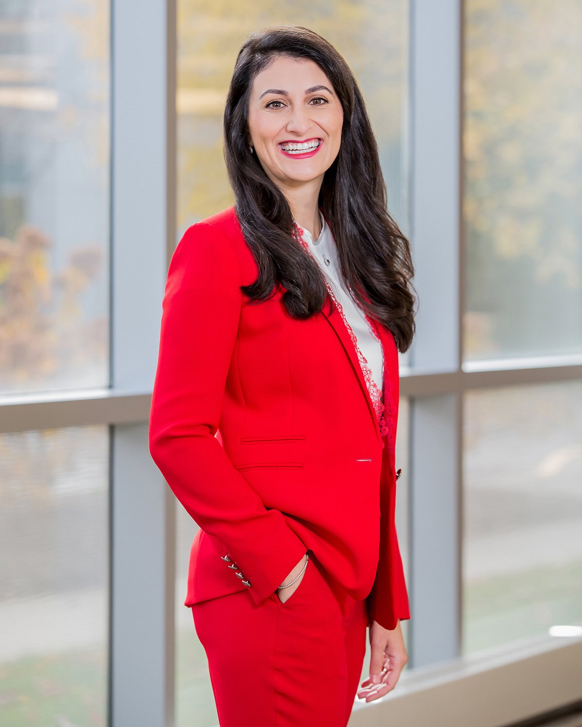 Smiling Ethnic Woman in a Red Suit in Front of Large Windows