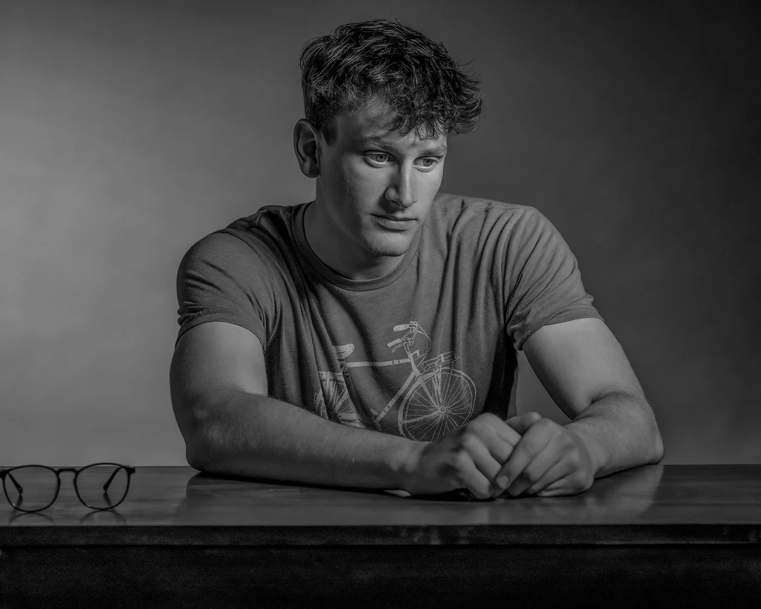 Black and White Studio Portrait of Young Man with Moody Lighting Looking Off Camera