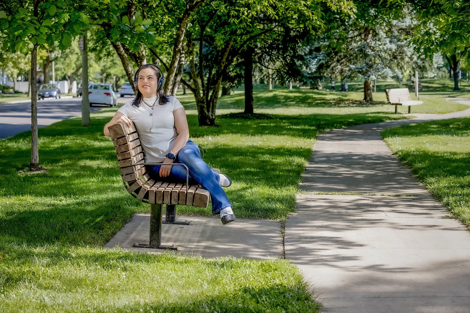 Young Woman Wearing Headphones Sitting on a Wooden Park Bench for Healthcare Campaign about Transplant Recipients