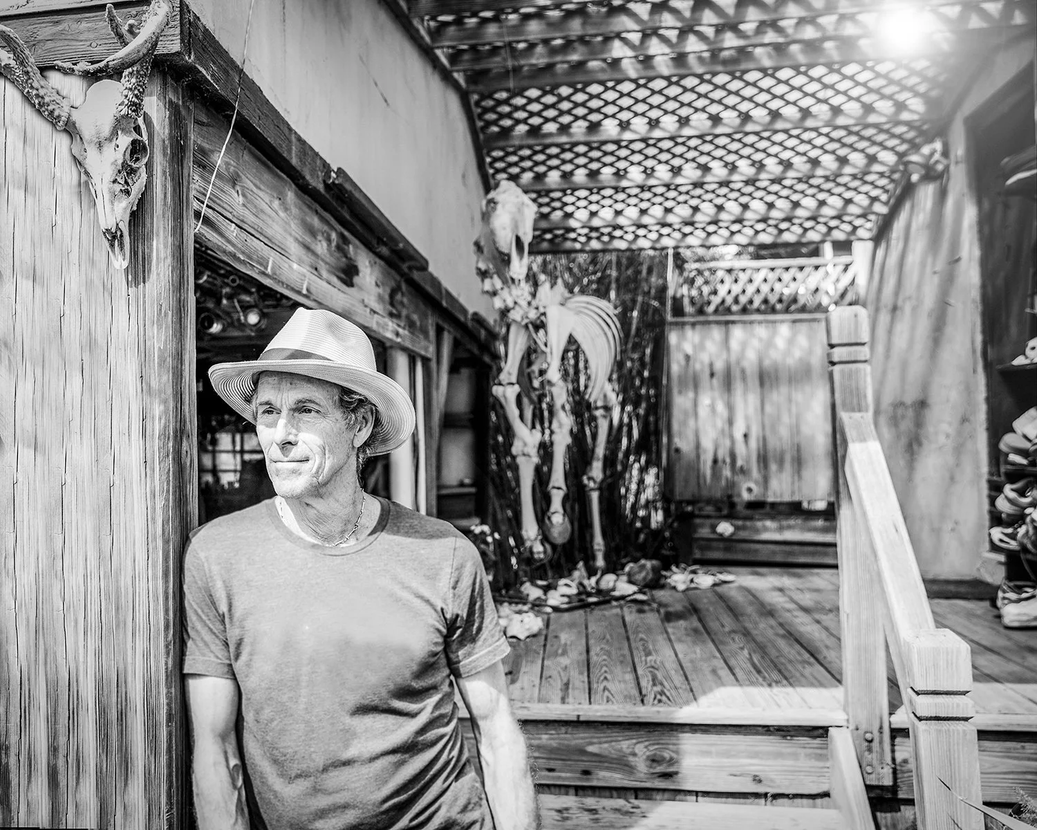Black and White Environmental Portrait of a Mature Man Wearing a Fedora Hat Leaning against Rustic Structure Ideal for Travel, Apparel or Editorial Advertising Campaigns