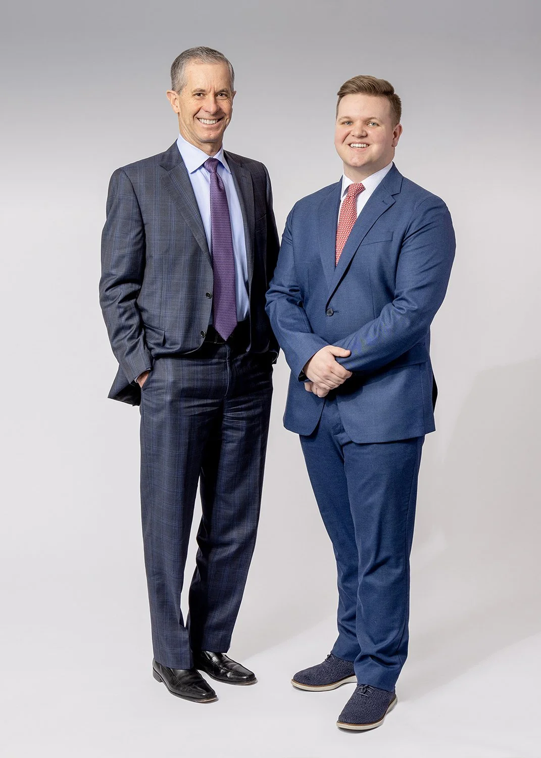 Corporate  Group Portrait of 2 Smiling Wealth Management Advisors Standing against a White Studio Background
