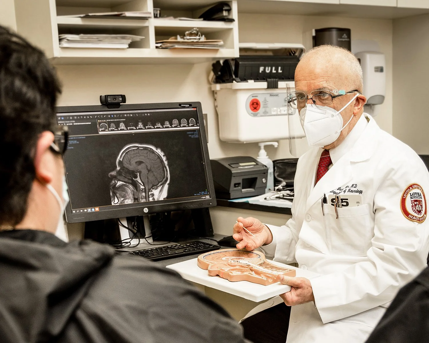 Doctor Wearing a Mask Discussing Brain Scans with his Patient.
