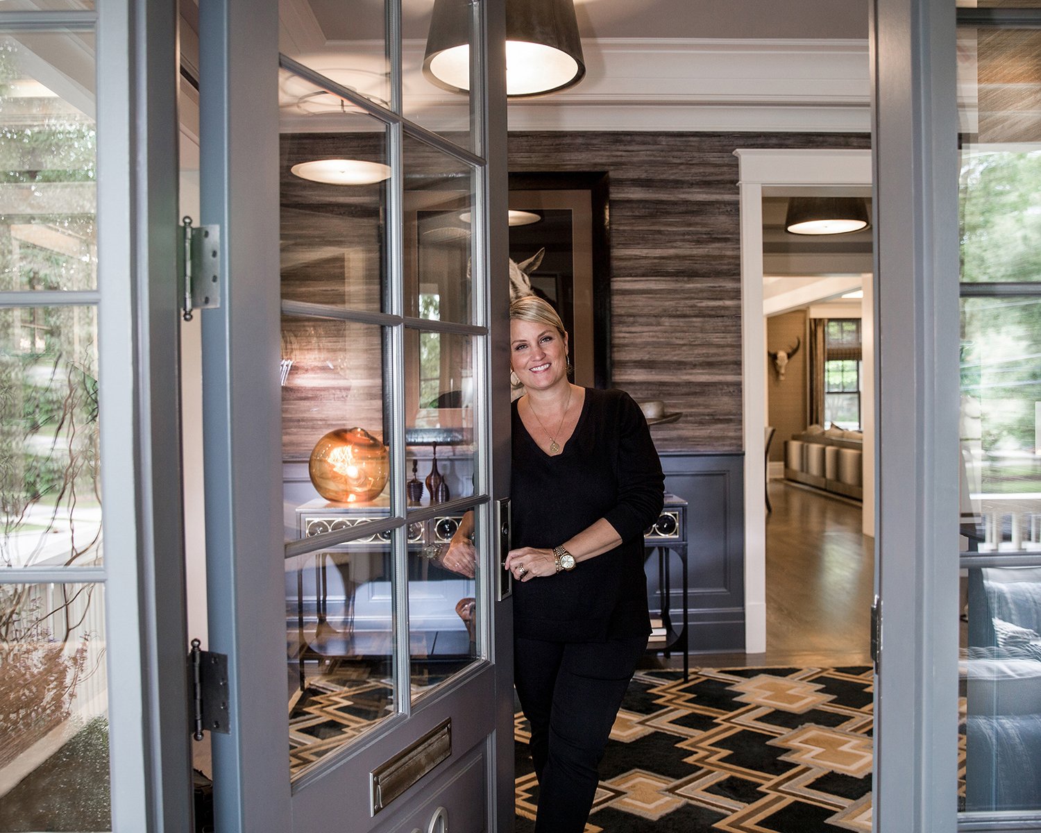 Portrait of a Woman Leaning on a Door Leading to Beautiful Entryway of Gorgeous Upscale Home. 