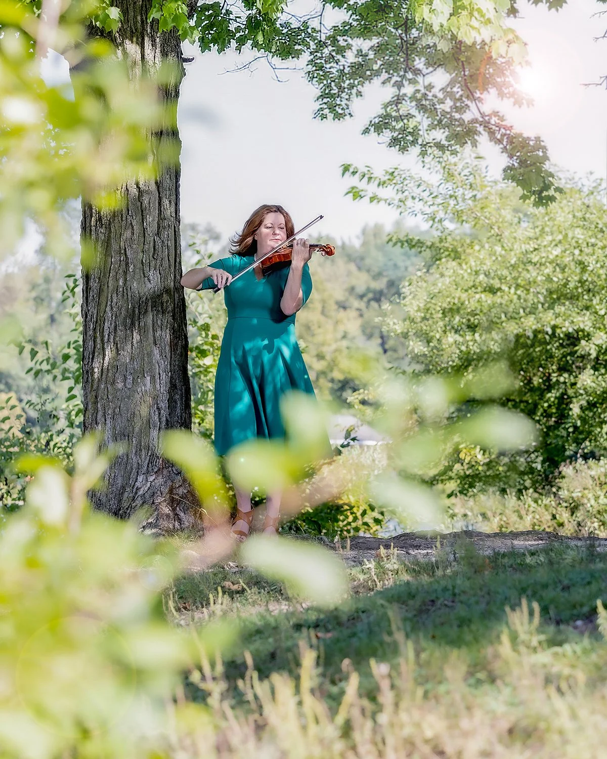 Woman Outside next to Trees Playing a Violin.  Lifestyle Photography