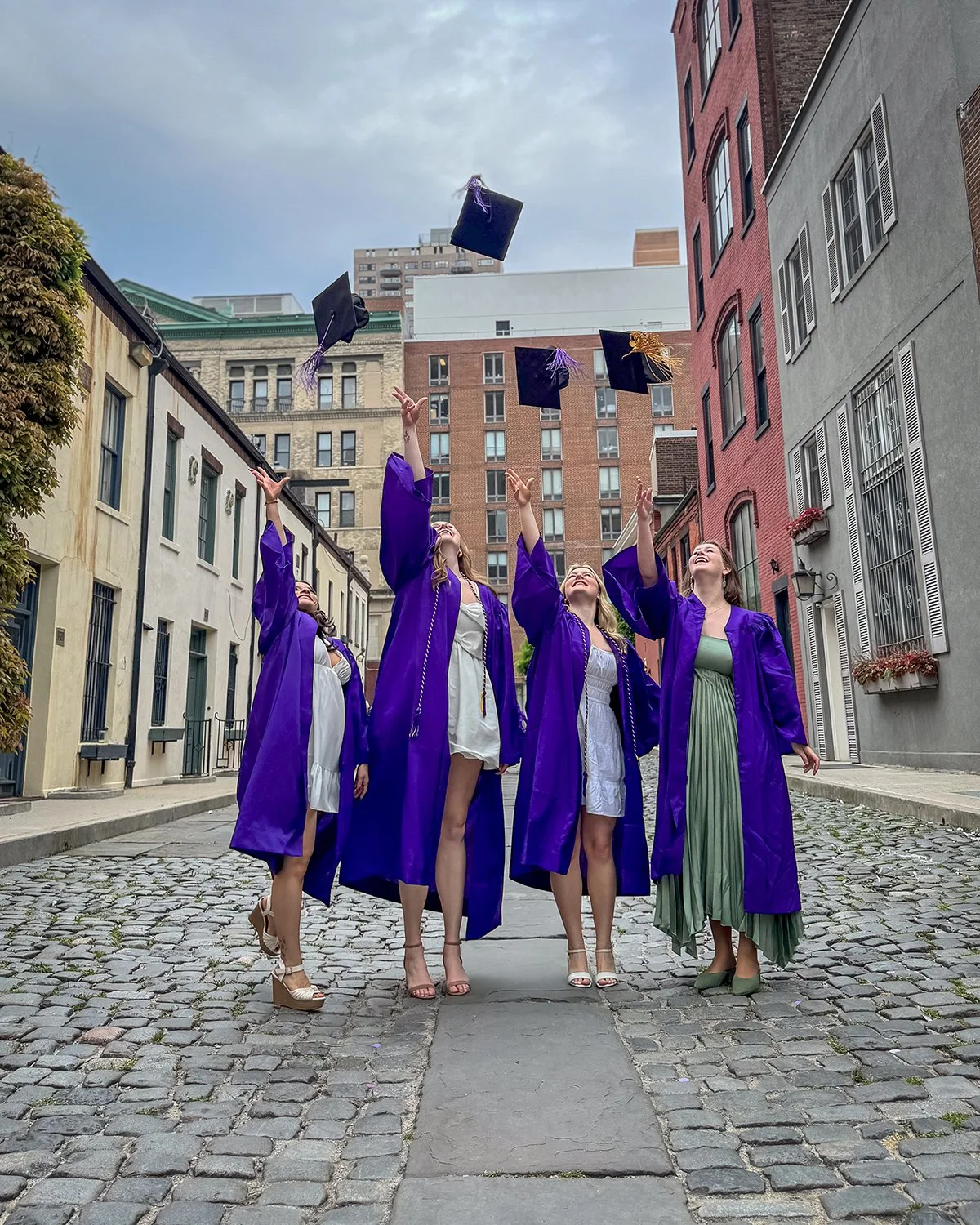 College Graduates Tossing Graduation Caps on City Street