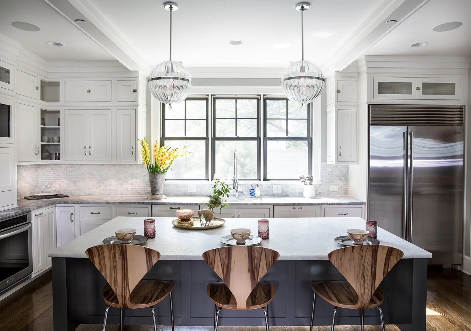 Chicago Interior Photography of a Bright Luxury Kitchen Interior with a Marble Island, White Cabinetry, and Three Modern Wood Bar Stools