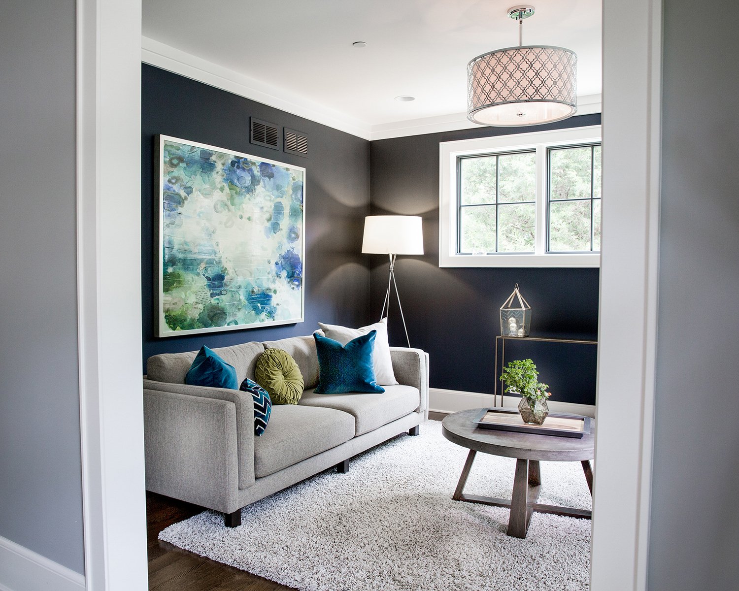 Modern Living Room Interior with Dark Navy Blue Walls, a Gray Sofa and a Large Abstract Blue Painting