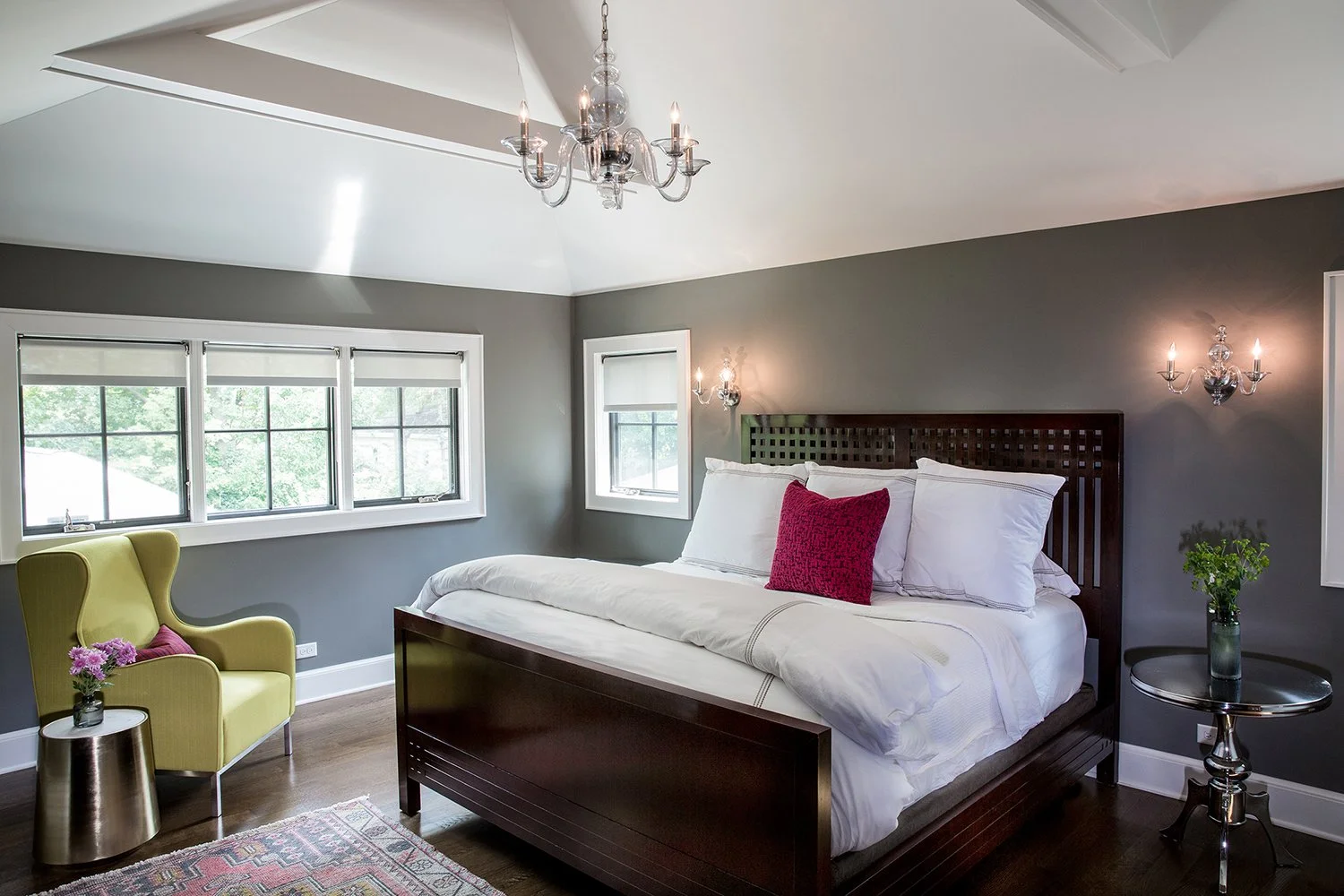 Wide-Angle Interior Photography of a Primary Bedroom with a Vaulted Ceiling, Crystal Chandelier, and Wall Sconces