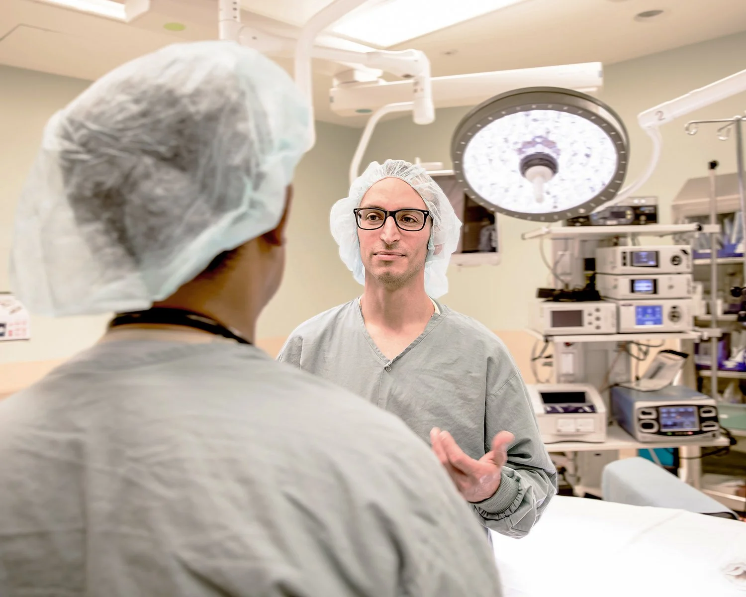 Two Doctors in Operating Room Talking. One with His Back to Camera while the Other is Gesturing with his Hand