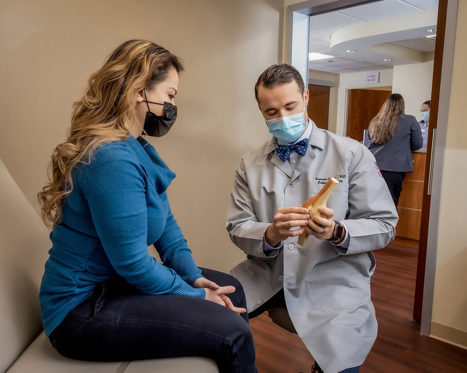 Male Doctor Explaining a Knee Injury and Potential Surgery to his Female Latino Patient using a Medical Prop