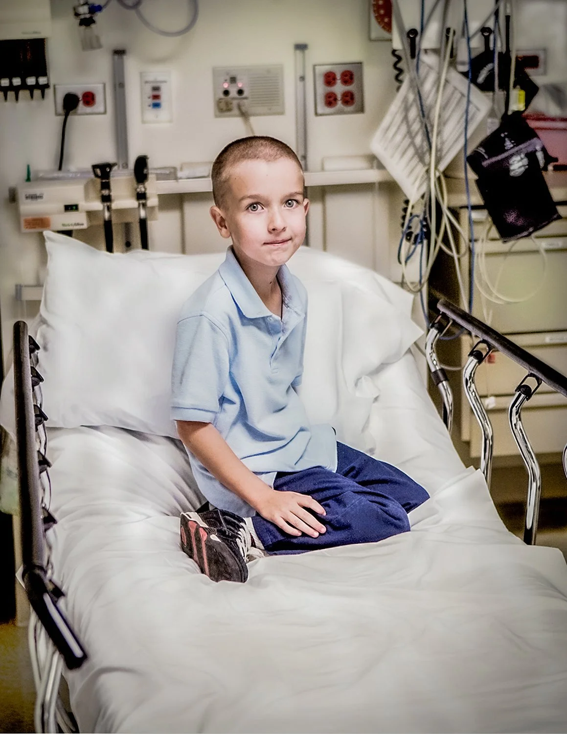 Portrait of Young Boy in Hospital Bed with Legs folded in Street Clothes