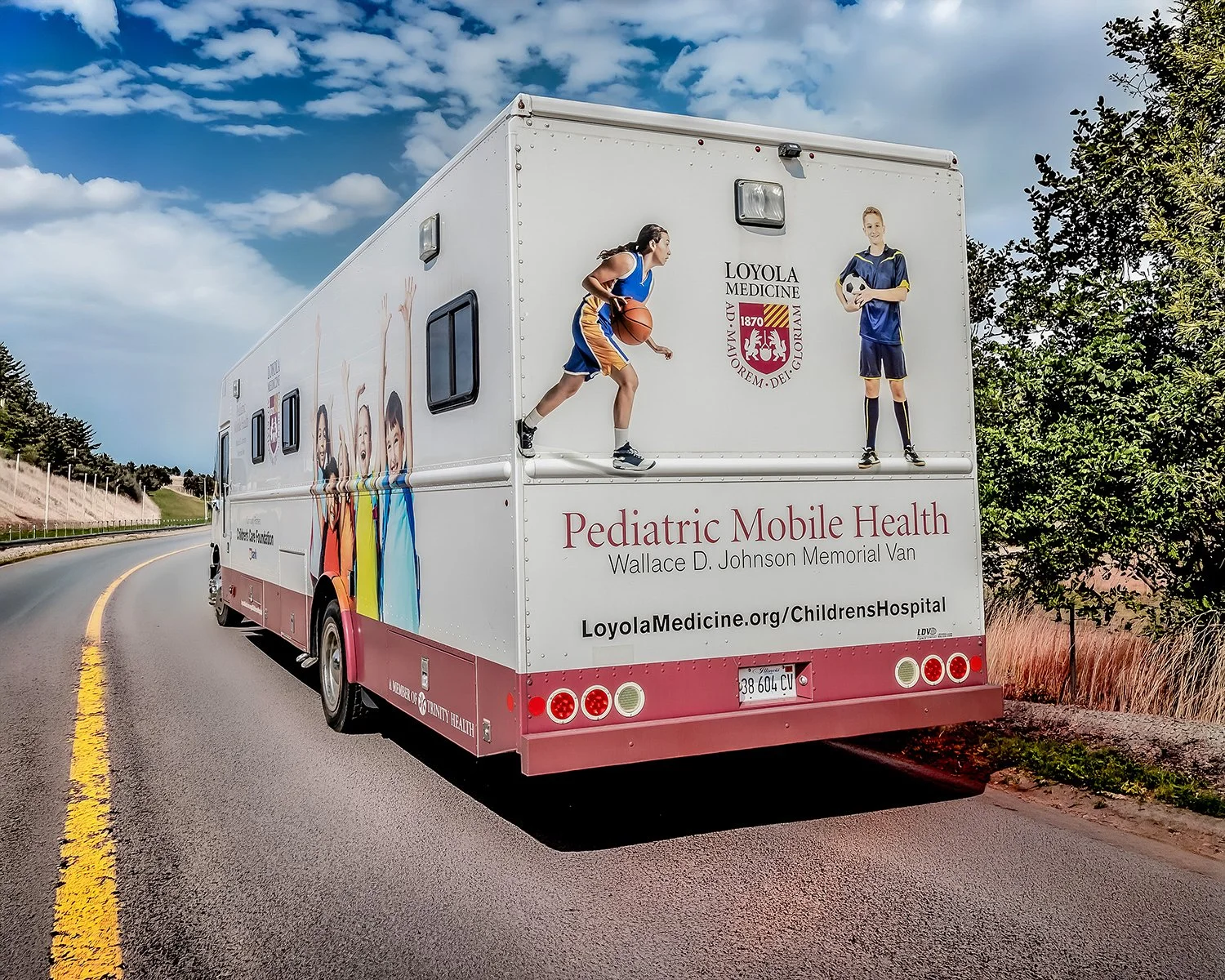 Pediatric Mobile Health Unit on the Road with Trees, Blue Sky and Clouds