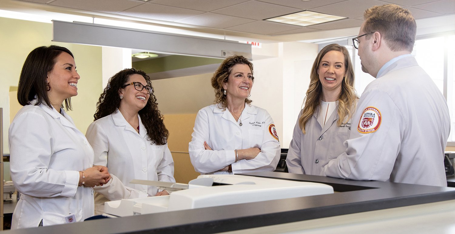 4 Women Doctors and 1 Male Doctor Talking, Smiling and Laughing in Medical Environment