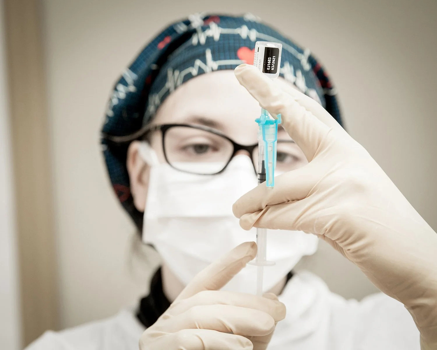 Female Nurse Closely Examining a Syringe in Medical Setting